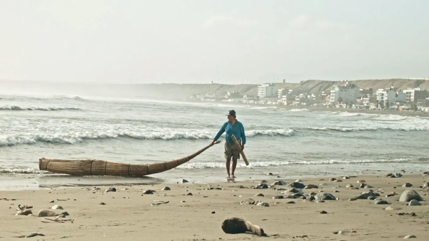 A fisherman beside a reed craft on the beach at Huanchaco